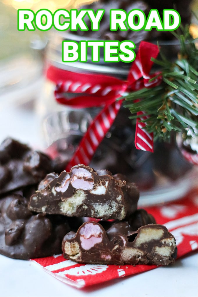 Rocky Road Bites cut in half to show the filings sat on a festive napkin in front of a jar of rocky road bites that has a red and white striped ribbon ties round the neck of the jar.